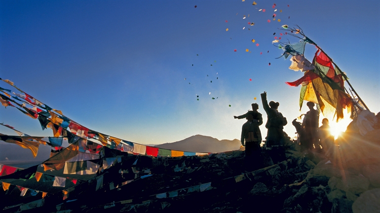中国西藏 ，朝圣者将风马旗扔向甘登寺上方的空中为新年祈福