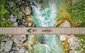 斯洛文尼亚索奇河上的木制吊桥上骑自行车的人的鸟瞰图 