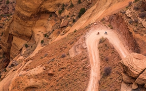 犹他州峡谷地国家公园 ，两名山地车骑手在白缘公路上沿着谢福小道的转弯处骑行 